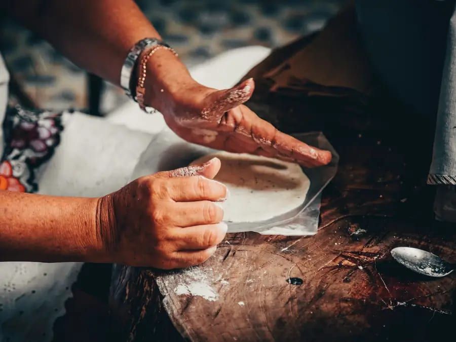 Hands pressing fresh masa into a tortilla