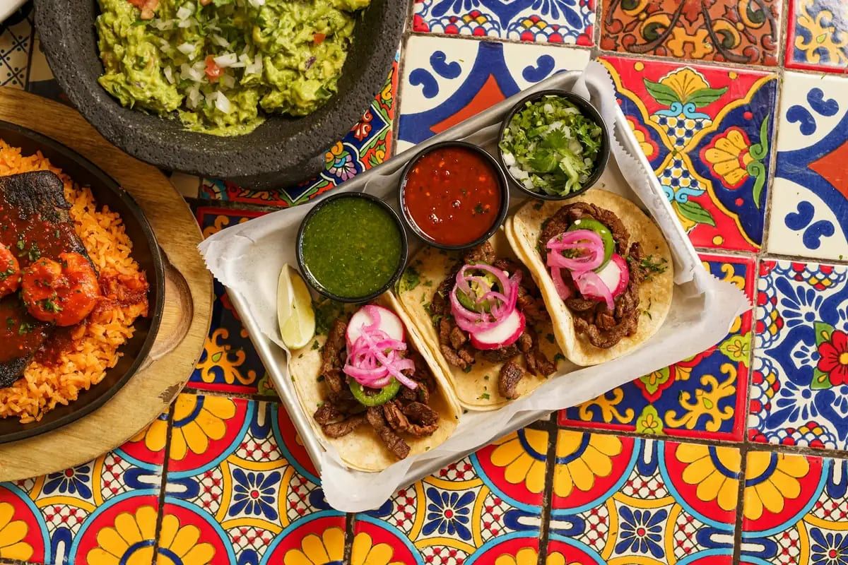Tacos, guacamole, salsas and rice on a Talavera-tile table